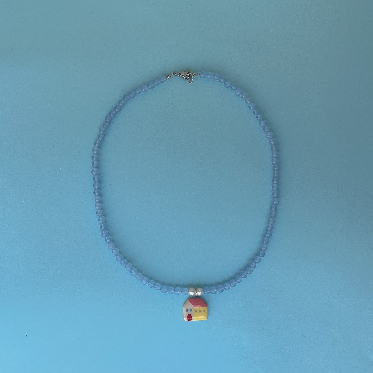 Collana azzurra con ciondolo casetta gialla