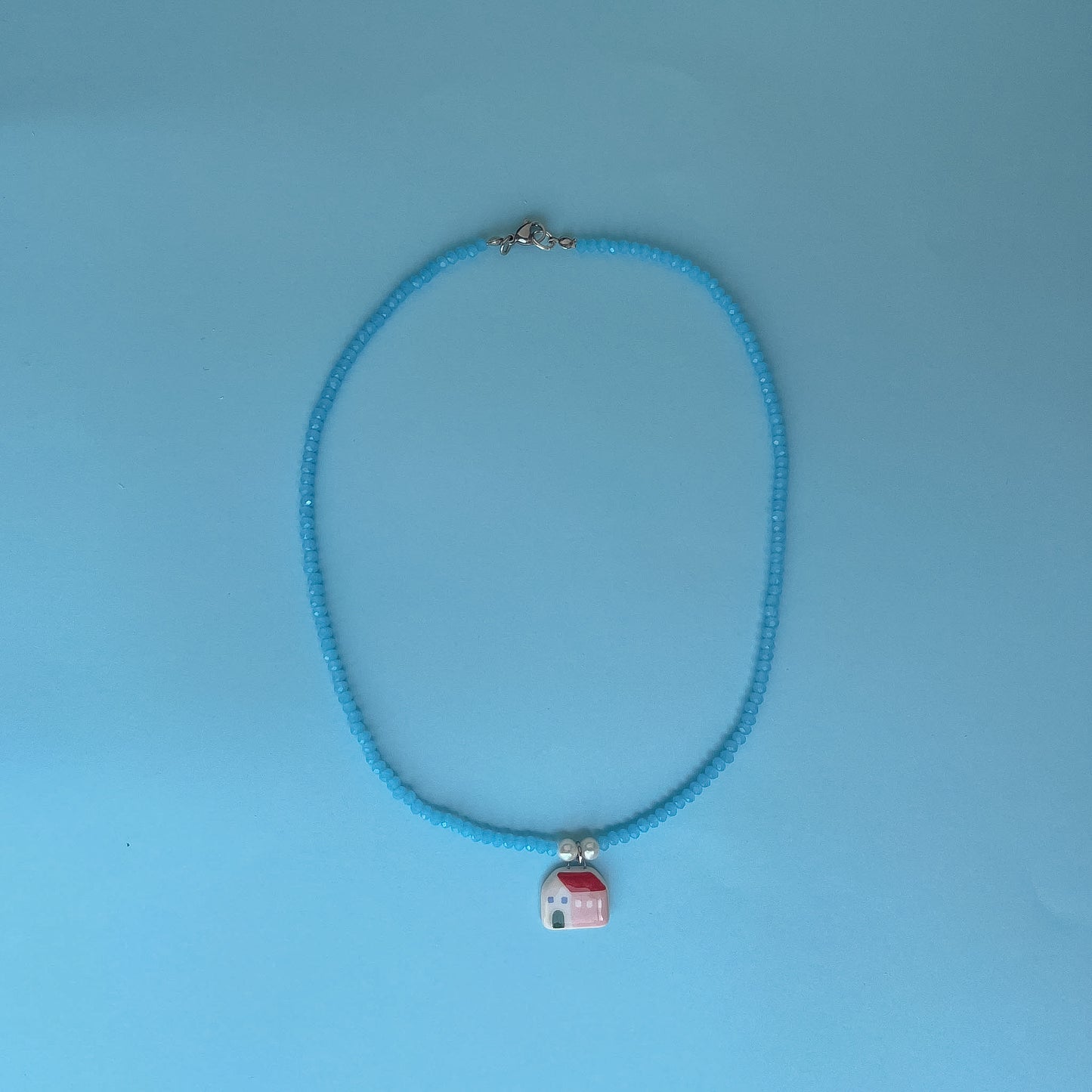 Collana azzurra con ciondolo casetta rosa